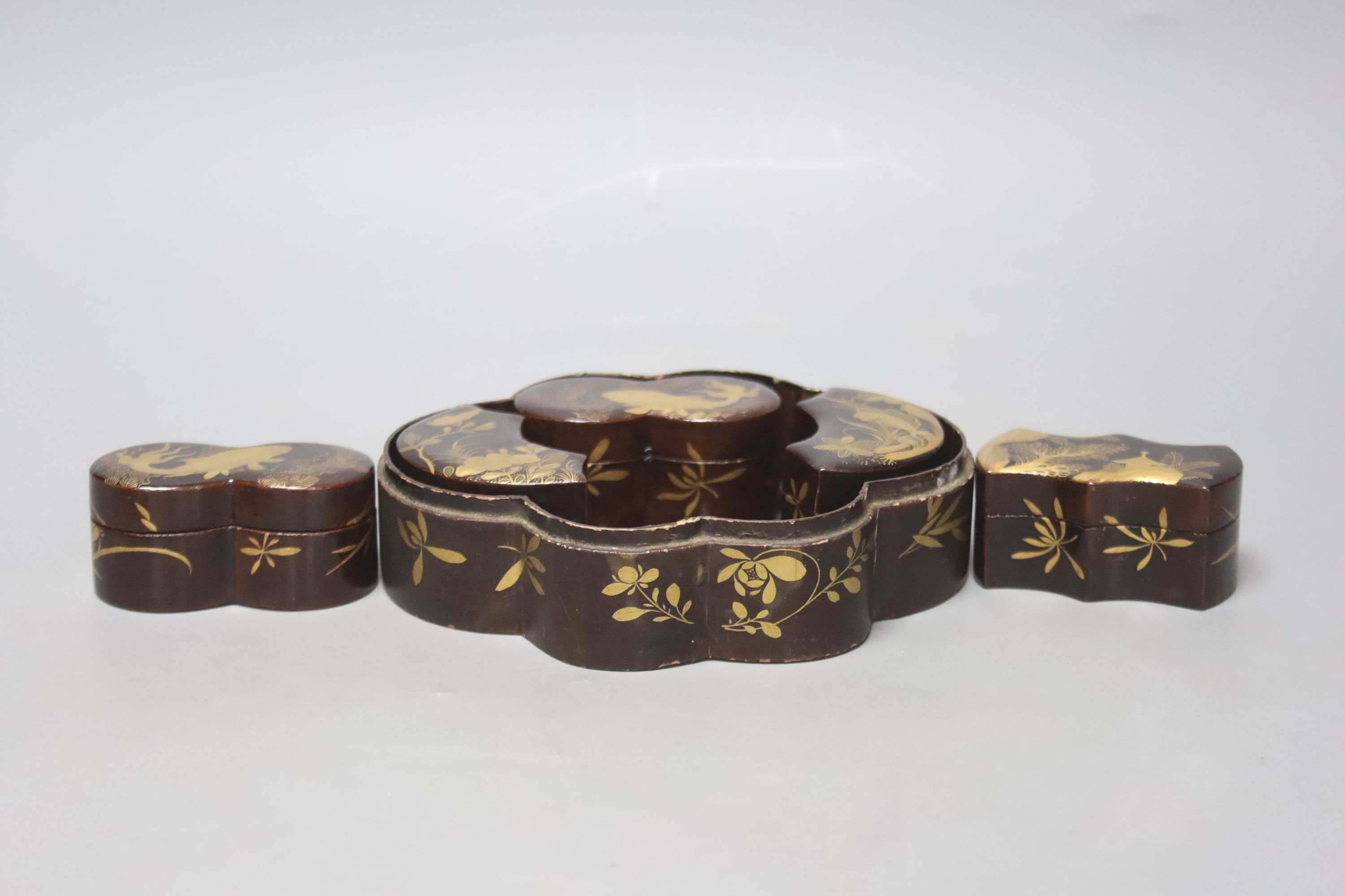 A Japanese black-lacquered box and cover, of shaped oval form, the top decorated in red and gilt with a stork on a branch, prunus, etc, L 16.5cm